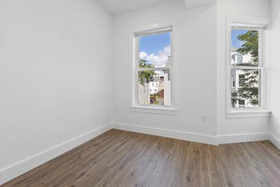 A room with a window showing a view of a residential area.