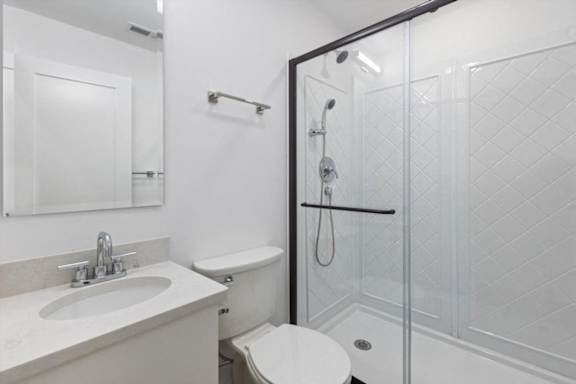 A white bathroom with a toilet, sink, and shower.