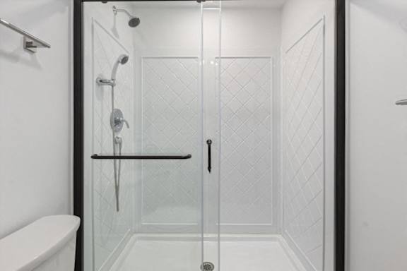 A white toilet is next to a walk-in shower with a glass door.