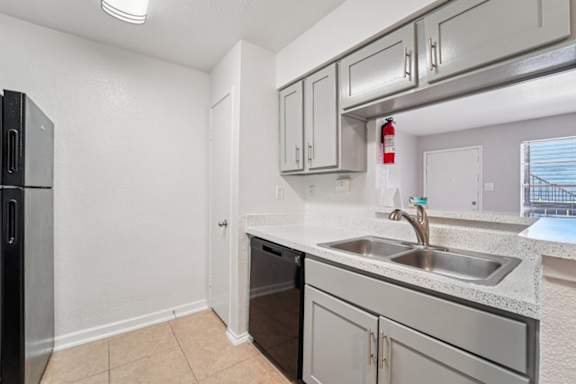 A kitchen with a black fridge and stainless steel appliances.