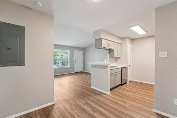 A kitchen area with a white countertop and wooden flooring.
