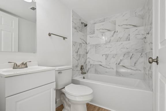 A white bathroom with a marble tile shower.