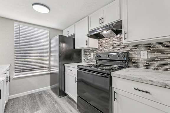 A kitchen with black appliances and white cabinets.