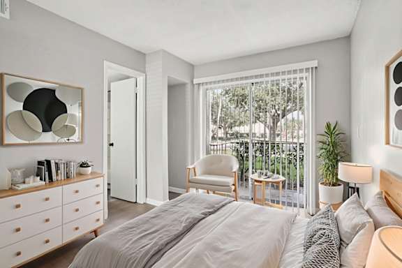 A bedroom with a large bed, a chair, and a window with a view of trees.