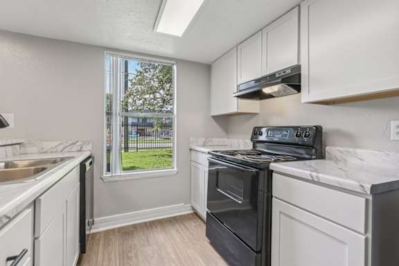 A kitchen with white cabinets and a black stove top oven.