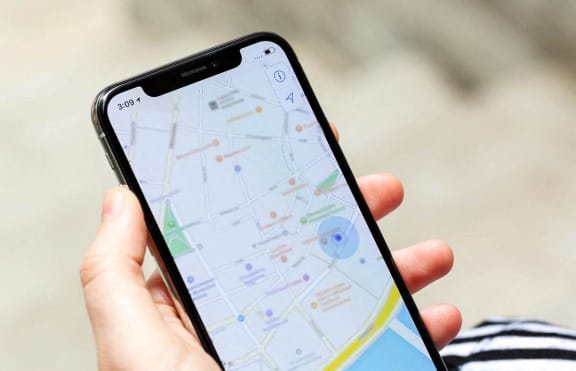 a hand holding an iphone with a map on the screen