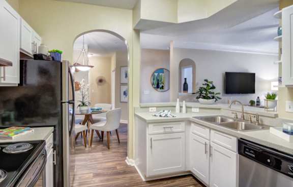A kitchen with a black fridge and a white counter.