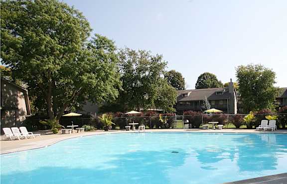 The poolside area at Eden West Apartments, featuring lounge chairs and a building in the background.