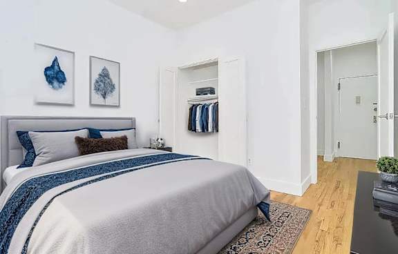 A bedroom with a large bed and a coat rack.