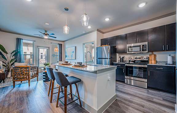 A modern kitchen with a bar area and a ceiling fan.