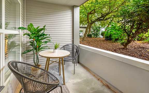 A patio with a chair, table, and potted plant.