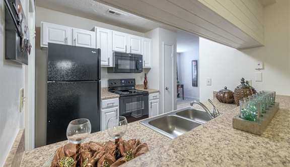 A kitchen with black appliances and white cabinets.