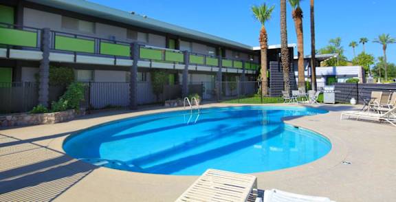 A pool surrounded by palm trees and a building.