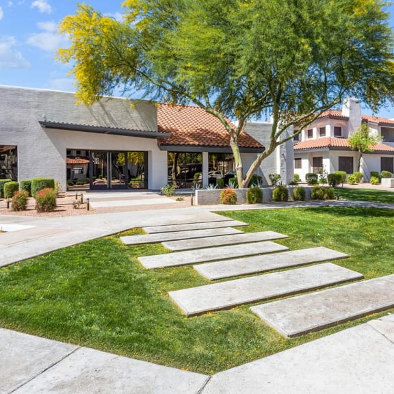 a grassy area with a stone walkway in front of a building