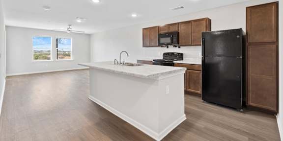 a kitchen with a large island and a black refrigerator