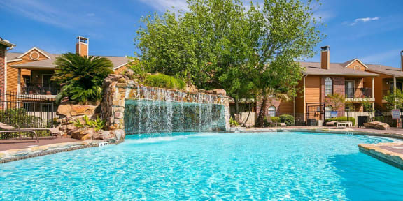 a large pool with a waterfall in front of a house at Oaks of Westlakes Apartments, San Antonio, 78245