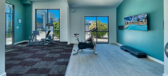 A room with a treadmill, exercise bike, and a painting on the wall.