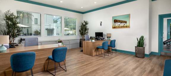 A room with blue chairs and a wooden desk.