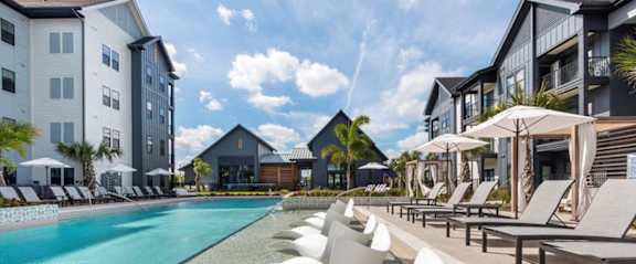A row of white chairs are lined up by a pool.