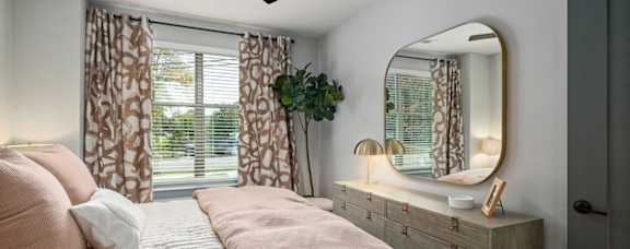 a bedroom with a bed and a mirror and a window