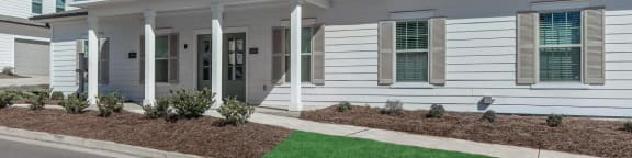 a white house with a lawn and sidewalk in front of it