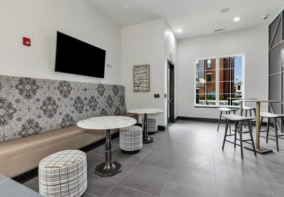 a seating area with stools and tables at the district flats apartments in lenexa,