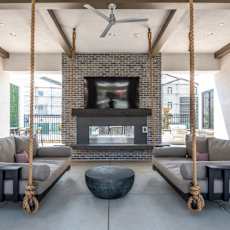 Outdoor lounge with a fireplace and two hanging sofas.