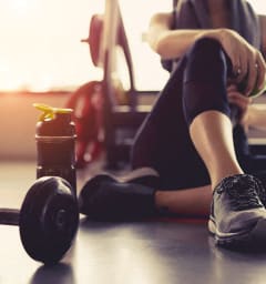 A woman is sitting on the floor with a dumbbell and a water bottle next to her. at Woodlands Creekside Apartments, Georgia, 30253