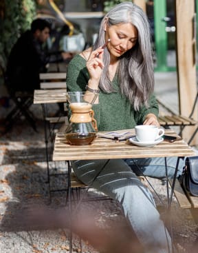 a woman sitting at a table with a cup of coffee at York House, Missouri, 63108