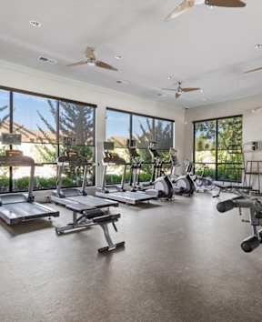 The fitness center with workout equipment such as treadmills, free weights and resistance machines at Stonepost Crossing Apartment Homes in Overland Park, Kansas.