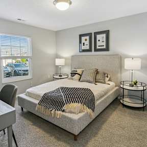 A bedroom with a bed, nightstand, and chair. at The Donovan Apartment Homes, Nebraska, 68516