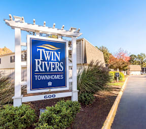 A sign for Twin Rivers Townhomes stands in front of a building.