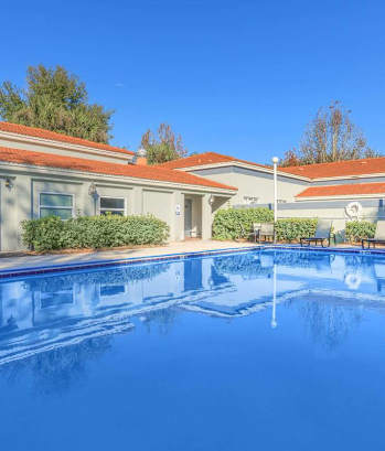 A large swimming pool in front of a building with a red roof at Oak Chase I, Tampa, FL