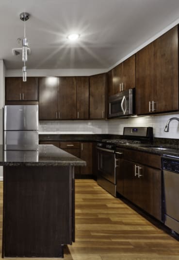a kitchen with dark wood cabinets and an island with granite countertops at West 130, New York