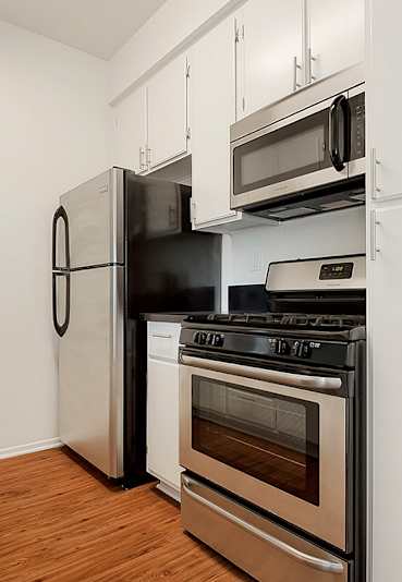 A kitchen with a black stove top oven and a black refrigerator.at Plaza Lafayette, Los Angeles California