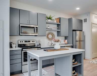 A modern kitchen with a white island and grey cabinets.