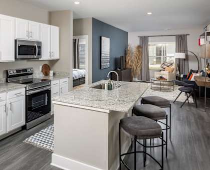 a kitchen with white cabinets and a large island with granite countertops at Fairview Springs in Covington, GA, 30016