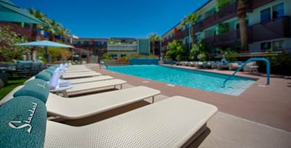 a pool with lounge chairs and umbrellas in front of a hotel