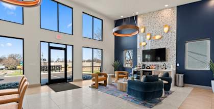 The Canvas Nashville apartments leasing office with coffee bar and seating area with navy blue and gold chairs.