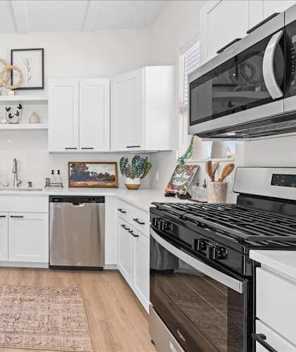 A modern kitchen with white cabinets and stainless steel appliances.