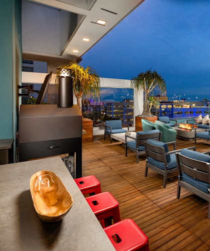 A wooden deck with blue chairs and a table with a bowl on it.