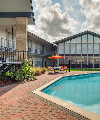 A swimming pool surrounded by a glass wall and a red umbrella.