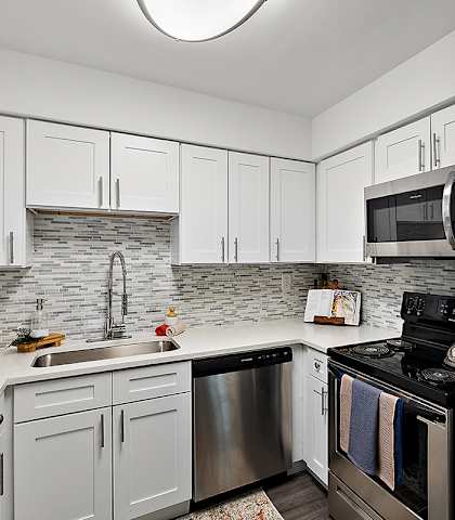 A kitchen with white cabinets and a stone backsplash.