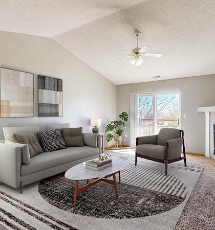 A virtually staged living room with a grey couch, a coffee table, a fireplace, and a television.