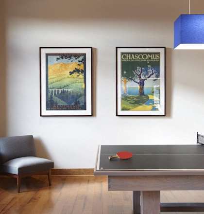 A room with a table, chair and two pictures on the wall.