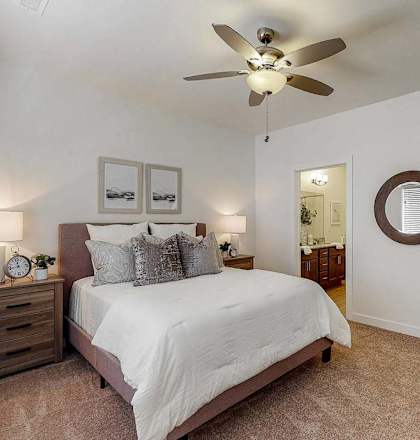 A bedroom with a bed, nightstand, and a ceiling fan.
