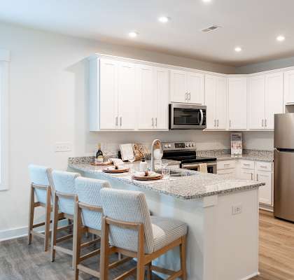 A kitchen with a refrigerator, microwave, oven, and sink.
