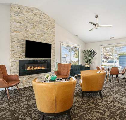 A living room with a stone fireplace and a fire burning inside.