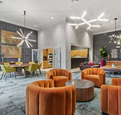 A modern living room with orange chairs and a grey wall.