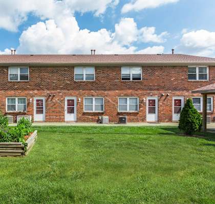 A red brick building with a green lawn in front.